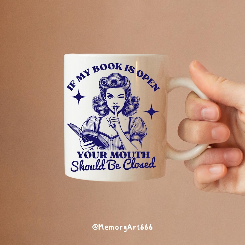 May include: White ceramic mug with a blue illustration of a woman holding a book and putting a finger to her lips. The text on the mug reads "If my book is open your mouth should be closed".