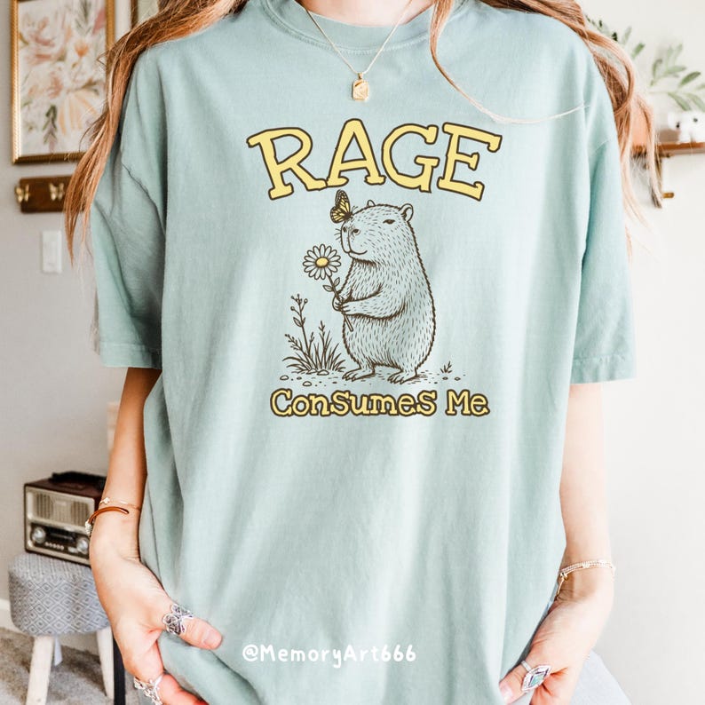 Funny capybara meme PNG SVG design featuring a cute vintage-style capybara holding a daisy flower with a butterfly resting on its head and bold retro “RAGE Consumes Me” typography. Funny sarcastic animal graphic with whimsical hand-drawn line art, soft neutral tones, and trendy unhinged aesthetic. Perfect for funny t-shirts, hoodies, mugs, tote bags, stickers, sublimation projects, Cricut SVG cut files, retro boutique apparel, instant digital download, 300 DPI transparent background.