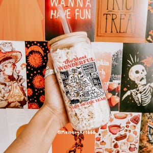 K&ouml;nnte beinhalten: Ein durchsichtiger Glasbecher mit Bambusdeckel und Strohhalm, gef&uuml;llt mit einer hellen Substanz. Der Becher zeigt eine schwarz-wei&szlig;e Grafik von Geistern, die B&uuml;cher lesen, mit dem Text "The Most Wonderful Haunted Bookstore Spooky Sale Time of the Year."