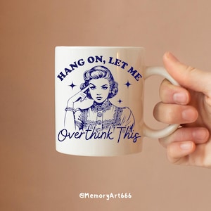 A vintage retro-style illustration of a 1950s woman with curled hair, resting her finger on her temple in a thoughtful pose. The text reads “HANG ON, LET ME” above and “Overthink This” below in playful retro typography. Monochrome hand-drawn line art with mid-century cartoon style and sparkle accents on a warm neutral background. Anxiety and mental health humor quote design, perfect for funny women’s shirts, mugs, tote bags, stickers, and digital crafts. Digital download SVG and PNG files.