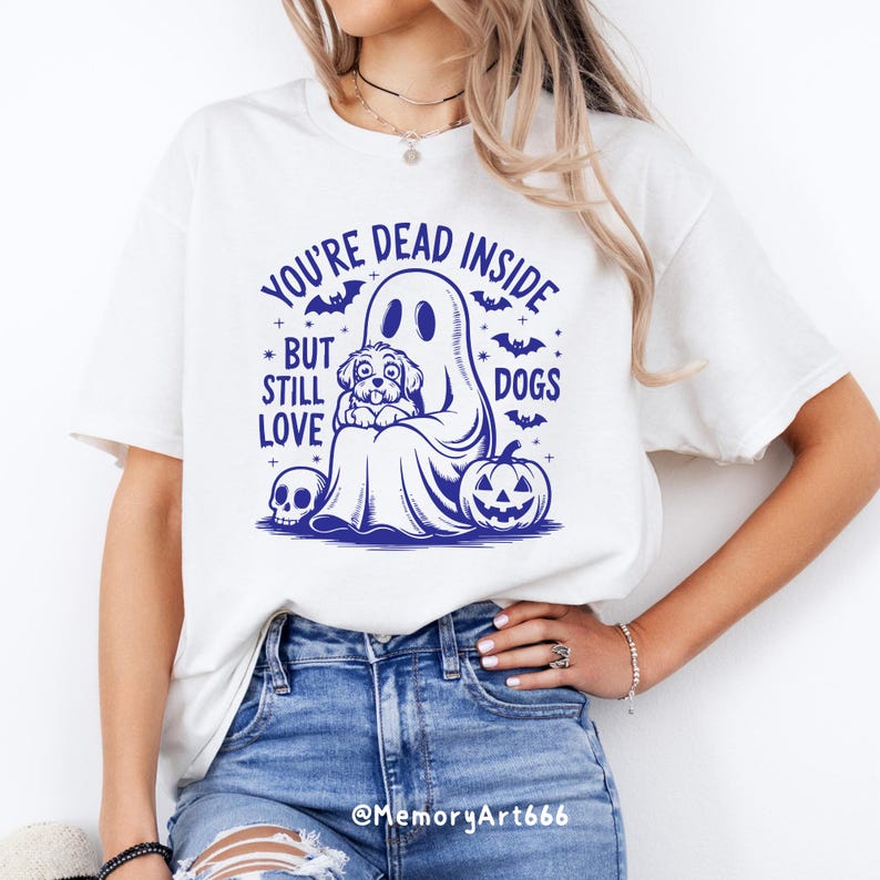 May include: White t-shirt with a blue graphic of a ghost holding a dog. The text on the shirt reads "You're Dead Inside But Still Love Dogs".