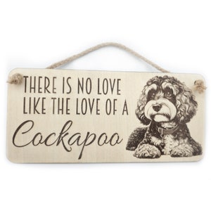 May include: A wooden sign with a brown string for hanging. The sign has a black and white image of a Cockapoo dog and the text "There is no love like the love of a Cockapoo."