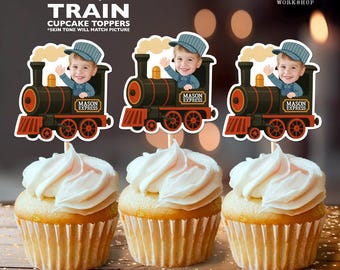 May include: Three cupcakes topped with white frosting, each adorned with a personalized train cupcake topper. The toppers feature a child's image in a conductor's hat, with the text "MASON EXPRESS". The toppers are 2.8 x 2.8 inches.