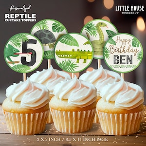 May include: A set of 6 round cupcake toppers featuring a green crocodile, a green snake, a green turtle, a green chameleon, a number 5, and a birthday message that says "Happy Birthday BEN". The toppers are printed on white cardstock with green and brown accents. The toppers are 5 cm in diameter.
