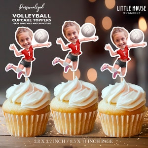 May include: Three personalised volleyball cupcake toppers featuring a cartoon girl in a red jersey and black shorts, holding a volleyball. The toppers are 2.8 inches by 3.2 inches and are printed on 8.5 inch by 11 inch paper.