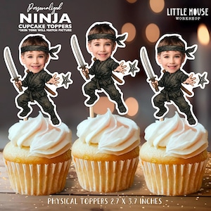 Puede incluir: Tres cupcakes con adornos con temática de ninja. Cada adorno presenta un ninja de dibujos animados con una espada y una estrella arrojadiza. Los cupcakes tienen glaseado blanco. El texto de la imagen dice "Personalized NINJA CUPCAKE TOPPERS" y "PHYSICAL TOPPERS 6,8 x 9,4 cm."