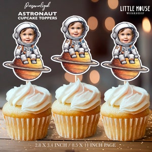 May include: Three astronaut cupcake toppers with a personalized photo of a child in the astronaut's helmet. The toppers are on a cupcake with white frosting. The toppers are 2.8 inches by 3.4 inches and the page is 8.5 inches by 11 inches.