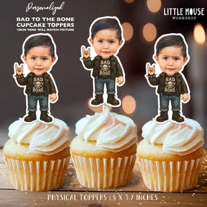 Pode incluir: Três cupcakes com toppers "Bad to the Bone". Cada topper apresenta um personagem de desenho animado com jaqueta de couro e jeans. Os cupcakes têm cobertura branca. O texto "Personalized Bad to the Bone Cupcake Toppers" está no topo. Medidas: 4.57cm x 9.4cm.