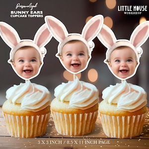 May include: Three white cupcakes with pink frosting topped with personalised bunny ear cupcake toppers featuring a baby's face. The toppers are 3 inches in size and are printed on 8.5 x 11 inch paper. The text "Personalized Bunny Ears Cupcake Toppers" and "Little Mouse Workshop" is printed on the image.