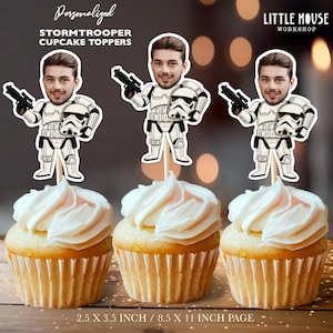 Puede incluir: Tres cupcakes con glaseado blanco, cada uno adornado con un adorno para cupcakes de Stormtrooper personalizado. Los adornos presentan la cara de un hombre en un cuerpo de Stormtrooper, sosteniendo un blaster y un casco. El texto dice "Personalized Stormtrooper Cupcake Toppers."
