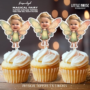 Op de afbeelding: Drie cupcakes met witte glazuur, elk bekroond met een Magical Fairy cupcake topper op maat. De toppers tonen een cartoonfee met een babygezicht en kleurrijke vleugels. De tekst luidt "MAGICAL FAIRY" en "PHYSICAL TOPPERS 7.6 x 7.6 cm".