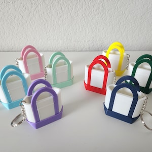 3D printed Trader Joe’s mini canvas tote bag keychain set in all 8 colors: red, blue, green, yellow, pastel pink, pastel purple, pastel green, pastel blue. Realistic miniature replica of the iconic Trader Joe’s shopping bag, perfect for keychains, backpacks, or as collectible bag charms. Handmade and eco-friendly, ideal gift for Trader Joe’s fans, foodies, or novelty accessory lovers. Great for collectors, stocking stuffers, or unique grocery-themed gifts.