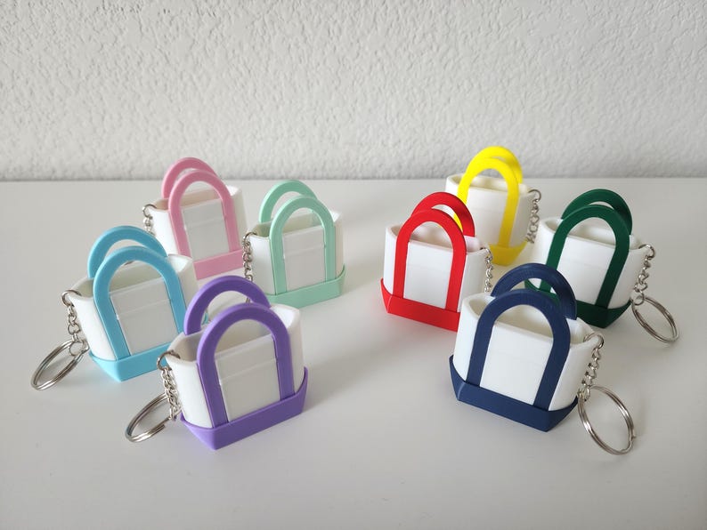 3D printed Trader Joe’s mini canvas tote bag keychain set in all 8 colors: red, blue, green, yellow, pastel pink, pastel purple, pastel green, pastel blue. Realistic miniature replica of the iconic Trader Joe’s shopping bag, perfect for keychains, backpacks, or as collectible bag charms. Handmade and eco-friendly, ideal gift for Trader Joe’s fans, foodies, or novelty accessory lovers. Great for collectors, stocking stuffers, or unique grocery-themed gifts.