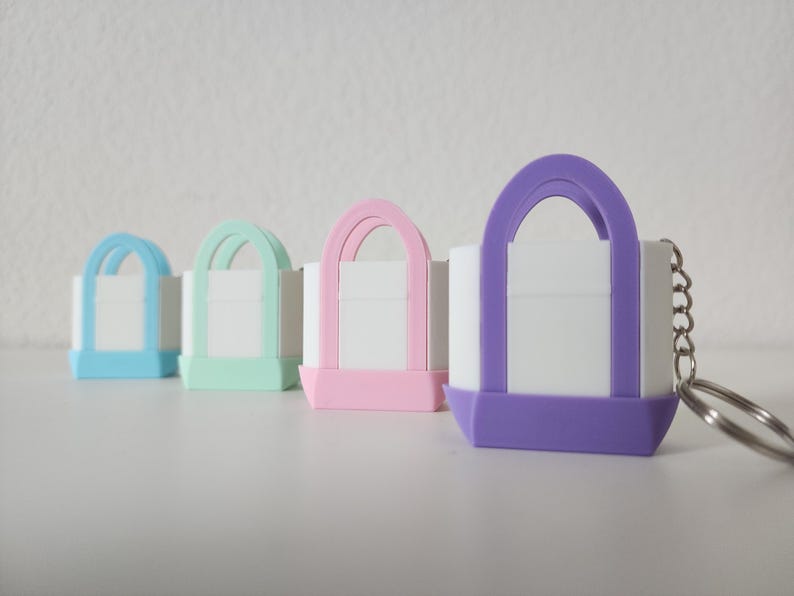 3D printed Trader Joe’s mini canvas tote bag keychain set in all 8 colors: red, blue, green, yellow, pastel pink, pastel purple, pastel green, pastel blue. Realistic miniature replica of the iconic Trader Joe’s shopping bag, perfect for keychains, backpacks, or as collectible bag charms. Handmade and eco-friendly, ideal gift for Trader Joe’s fans, foodies, or novelty accessory lovers. Great for collectors, stocking stuffers, or unique grocery-themed gifts.