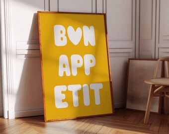 May include: A yellow framed poster with white text that reads "BON APP ETIT" with a heart in place of the "O" in "BON".