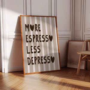 May include: A framed print with a striped background and the text "More Espresso Less Depresso" with a heart symbol after each word.