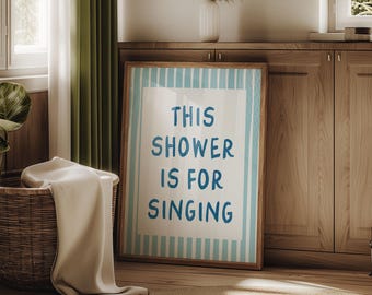May include: A framed print with blue and white stripes and the text "This shower is for singing" in blue.