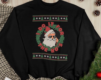 May include: Black sweatshirt with a graphic of Santa Claus wearing sunglasses and the text "I DO IT FOR THE HO'S" in a wreath design. The sweatshirt has a green and red Christmas tree pattern at the top and bottom.