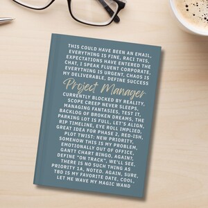 May include: A blue notebook featuring white text that reads: This could have been an email, everything is fine, Raci this, expectations have entered the chat, I speak fluent corporate, everything is urgent, chaos is my deliverable, define success, Project Manager.