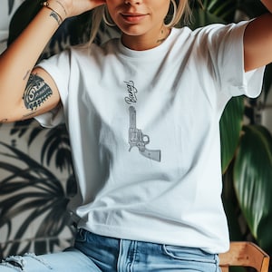 May include: White t-shirt with a black and white illustration of a revolver and the word "Bang!" printed on the front.