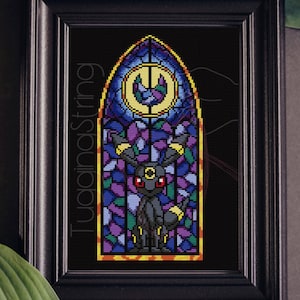 May include: Framed cross-stitch art featuring a black Umbreon character in a stained-glass window design. The window has a blue, purple, and yellow color scheme. The frame is black, and the text "TugainaString" is visible on the left side.