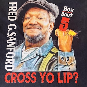 以下が含まれることがあります： サンフォード家の息子たちというテレビ番組のフレッド・G・サンフォードの写真がプリントされた黒いTシャツ。Tシャツには「How Bout 5 Cross Yo Lip?」という赤い文字がプリントされています。