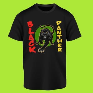 May include: Black t-shirt featuring a black panther illustration inside a green circle. The words "BLACK" and "PANTHER" are printed vertically on either side of the panther in red and yellow, respectively. The panther is depicted with its mouth open.