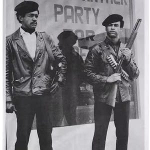 May include: Black and white photo of Bobby Seale and Huey P. Newton, co-founders of the Black Panther Party. The photo is in front of a sign that reads "Black Panther Party".