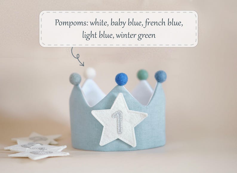 Op de afbeelding: Een lichtblauwe kroon van vilt met een witte viltster en het getal "1" erop geborduurd. De kroon is versierd met pompoenen in wit, babyblauw, Frans blauw, lichtblauw en wintergroen.