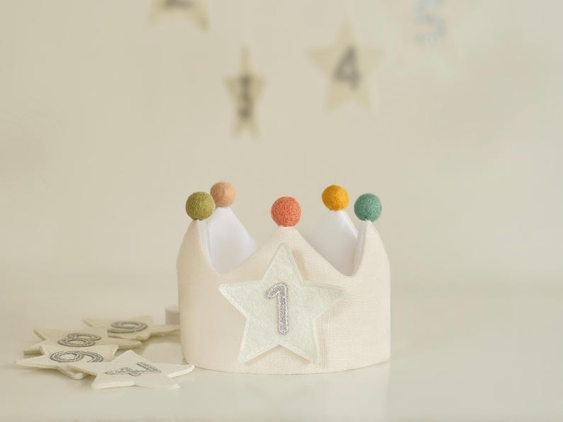Op de afbeelding: Een witte viltkroon met een ster en het nummer &eacute;&eacute;n erop. De kroon is versierd met gekleurde viltballetjes.