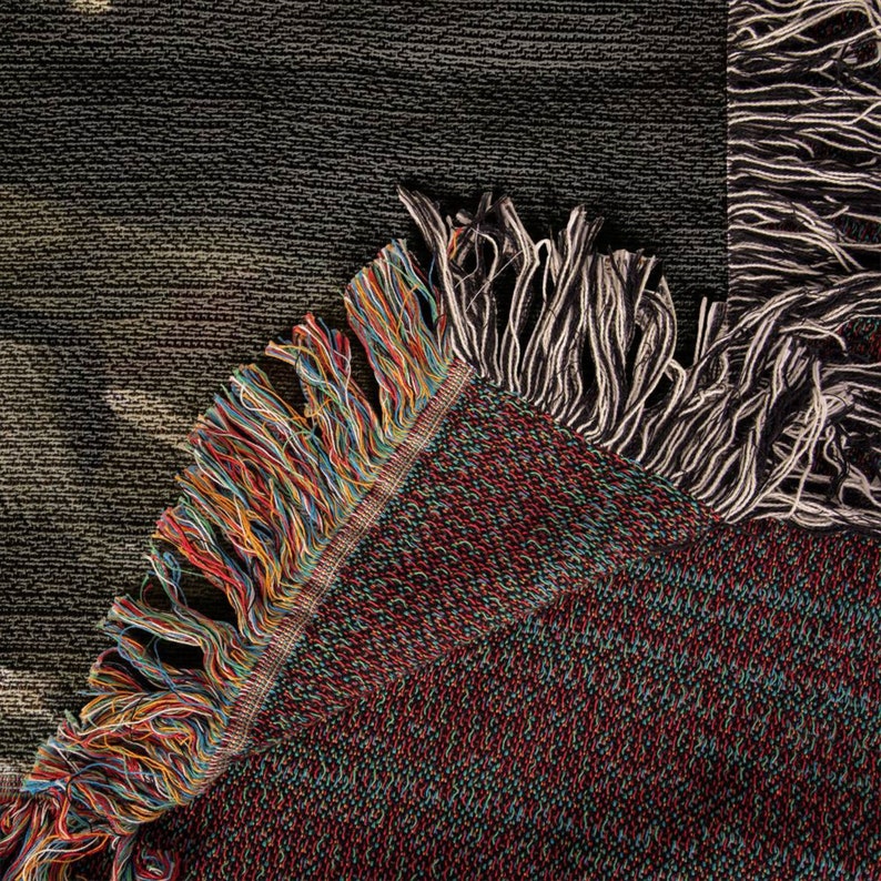 May include: Close-up of a woven tapestry with a colorful fringe. The tapestry is made of a variety of colors, including red, blue, green, and yellow. The fringe is made of a variety of colors, including black, white, and brown.