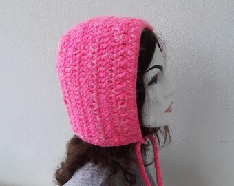 May include: A pink crocheted hat with a long tie. The hat is made with a textured yarn and has a simple design.