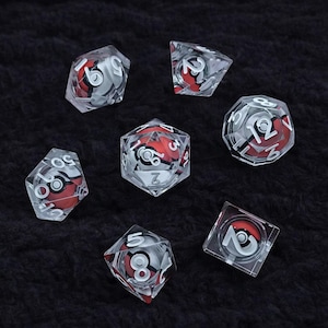 Pode incluir: Conjunto de sete dados transparentes multifacetados com um design vermelho e branco no interior. Cada dado apresenta números brancos e um design de bola vermelha e branca. Dispostos sobre uma superfície escura e texturizada.