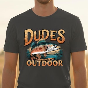 Könnte beinhalten: Dunkelgraues T-Shirt mit einer farbenfrohen Illustration eines Fisches und den Worten "Dudes Outdoor" in einer stilisierten Schriftart. Das Design umfasst einen Fisch, Wasser und Blätter.