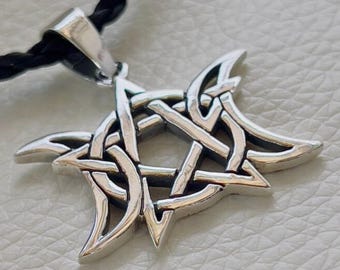 May include: A silver pendant necklace featuring a triple moon symbol with a pentagram inside. The pendant is made of intricate knotwork and has a black cord.