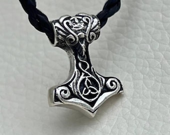 Peut inclure: Un collier avec un pendentif en argent représentant un marteau avec un nœud celtique. Le pendentif est attaché à un cordon tressé noir.