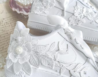 May include: A white ceramic mug with a black handle and the text "But First, Coffee" in a black, handwritten-style font. The mug is on a white surface.