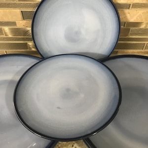 May include: Four blue and white ceramic dinner plates with a swirl design. The plates are stacked on top of each other.