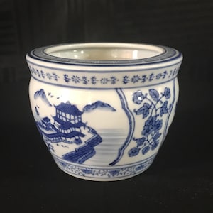 Könnte beinhalten: Ein kleiner, weißer Keramiktopf mit einem blauen und weißen Blumendesign. Der Topf zeigt eine Szene mit einem traditionellen chinesischen Gebäude mit Bergen und Wasser im Hintergrund.
