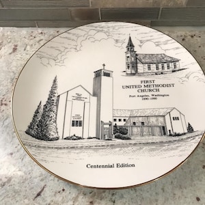 Könnte beinhalten: Eine weiße Platte mit goldenem Rand. Sie zeigt eine Schwarz-Weiß-Illustration der First United Methodist Church in Port Angeles, Washington. Die Platte ist eine Centennial Edition, mit dem Namen der Kirche und den Daten 1890-1990.