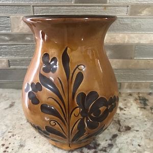May include: A ceramic vase with a glossy finish, featuring a warm brown base and dark brown floral designs. The vase has a flared top and a rounded body, showcasing a traditional aesthetic.
