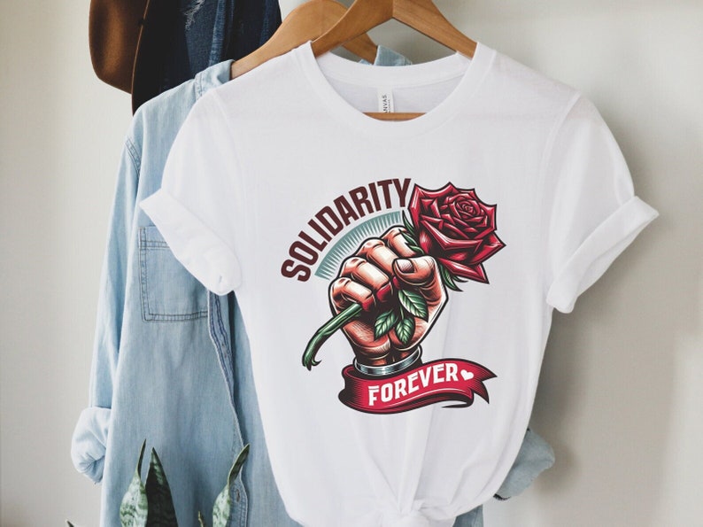 May include: White t-shirt with a graphic of a fist holding a red rose with green leaves. The text "SOLIDARITY FOREVER" is printed on a red ribbon.