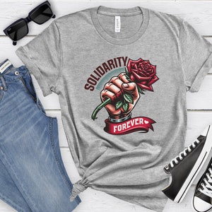 May include: Gray t-shirt with a graphic of a fist holding a red rose with the text "Solidarity Forever" printed on it.