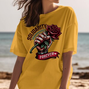 May include: Yellow t-shirt with a graphic of a hand holding a red rose with the text "Solidarity Forever" on a banner.