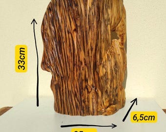 May include: A handcrafted wooden sculpture with a natural, textured finish. The piece is 33cm tall, 25cm wide, and 6.5cm deep. The wood grain is visible, showcasing the natural color variations of the material. The sculpture has a unique, organic shape.