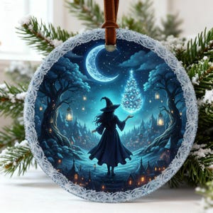 Könnte beinhalten: Runder Weihnachtsschmuck mit einer Hexe in einem dunkelblauen Kleid und Hut, die vor einem leuchtenden Weihnachtsbaum und einem Halbmond steht. Der Schmuck hat eine detaillierte Winterszene mit silbernem Spitzensaum und einem braunen Band zum Aufhängen.