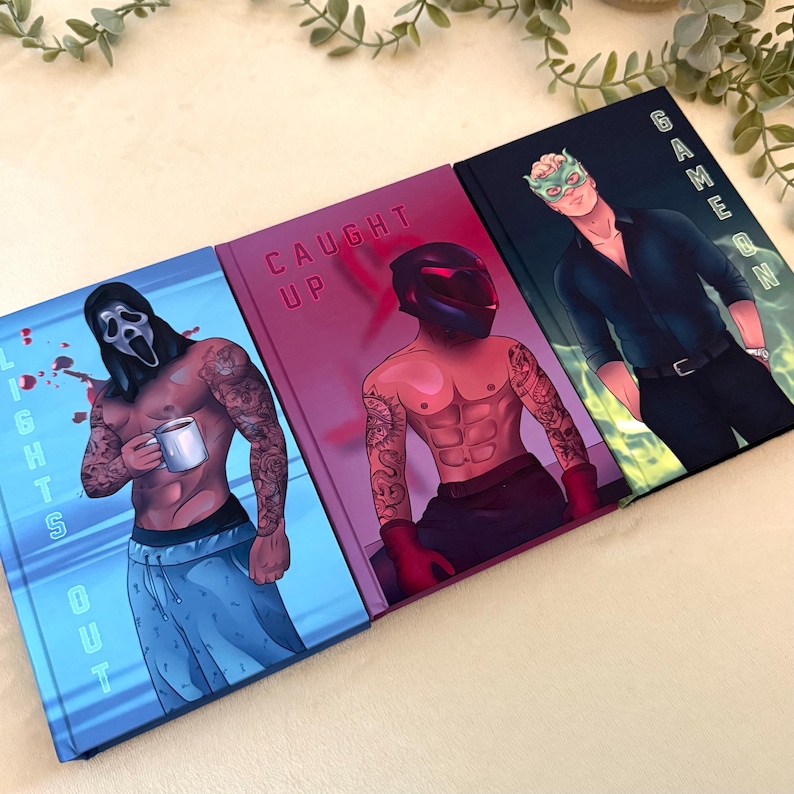 May include: Three hardcover books with illustrated covers. The left book is blue with the text LIGHTS OUT and a masked figure holding a mug. The middle book is magenta with CAUGHT UP and a helmeted figure. The right book is dark with GAME ON and a masked man.