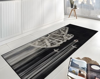 May include: A black and white area rug with a graphic of a spaceship and fighter jets flying in formation. The rug is in a kitchen setting with white cabinets and a window in the background.