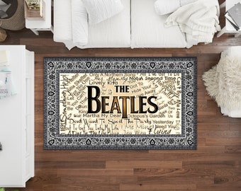 May include: A beige and black rug with a white border featuring a word cloud of The Beatles song titles. The word "Beatles" is in large, gold letters in the center of the rug.
