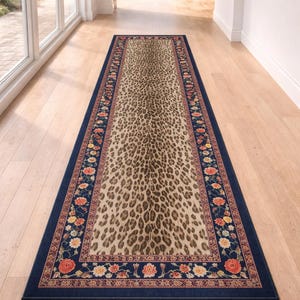 May include: A rectangular runner rug with a leopard print center and a navy blue border. The border features a floral pattern in shades of red, orange, yellow, and cream. The rug is placed on a light-colored wooden floor.